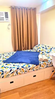 a bed with a blue comforter and a curtain at Veronica Grey's Staycation 2BR in Manila