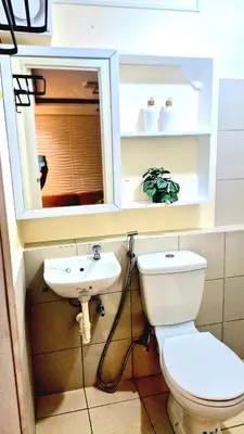 a bathroom with a toilet and a sink and a mirror at Veronica Grey's Staycation 1BR in Manila