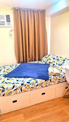 a bed with a blue comforter and a curtain at Veronica Grey's Staycation 1BR in Manila