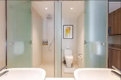 a bathroom with a glass shower and a toilet at Novotel Executive Hotel at Rosalina Acqua Residence in Manila
