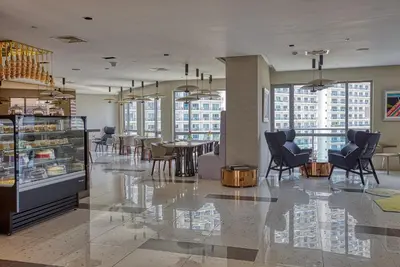a restaurant with chairs and tables in a building at Novotel Executive Hotel at Rosalina Acqua Residence in Manila
