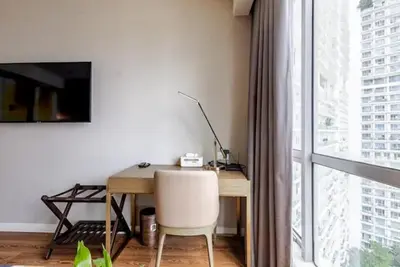 a desk with a chair in a room with a window at Novotel Executive Hotel at Rosalina Acqua Residence in Manila