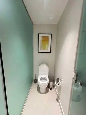 a bathroom with a white toilet in a room at Novotel Executive Hotel at Rosalina Acqua Residence in Manila