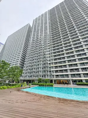 a large building with a pool in front of it at Eastovia Suites city center condo with pool at Fame in Manila