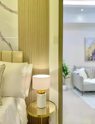 a bedroom with a bed and a table with a lamp at Eastovia Suites city center condo with pool at Fame in Manila