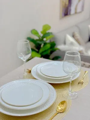 a table with two white plates and two wine glasses at Eastovia Suites city center condo with pool at Fame in Manila