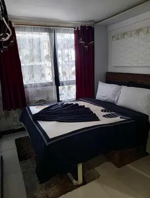 a bedroom with a bed and a window with red curtains at ADB Ortigas Tower in Manila