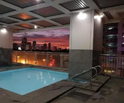 a swimming pool on the roof of a building with a sunset at ADB Ortigas Tower in Manila