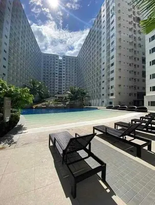 a large building with a pool with benches in front of it at StayWisePH at MOA in Manila