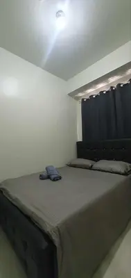 a bedroom with a large bed with a black headboard at StayWisePH at MOA in Manila