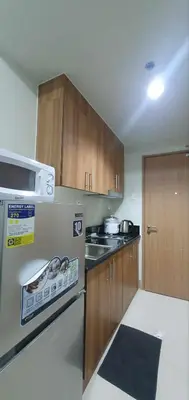 a kitchen with wooden cabinets and a white refrigerator at StayWisePH at MOA in Manila