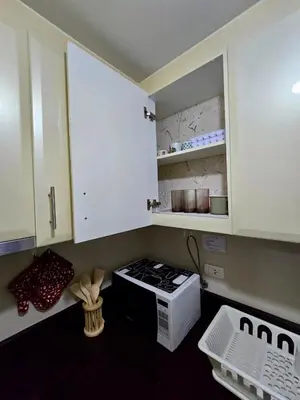 a kitchen with white cabinets and a stove top oven at Newport 150 - 1 BR staycation near NAIA 3 in Manila