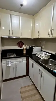 a kitchen with white cabinets and a sink at Newport 150 - 1 BR staycation near NAIA 3 in Manila