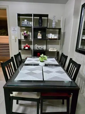 a dining room table and chairs with a table and a shelf at Newport 150 - 1 BR staycation near NAIA 3 in Manila