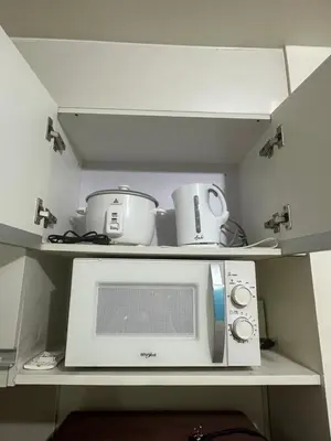 a microwave and pots and pans on a shelf at Relaxing Pasay Retreat Pool & WiFi - Harlhy in Manila