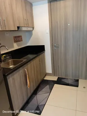 a kitchen with wooden cabinets and a sink and a door at Coast Residences in Manila