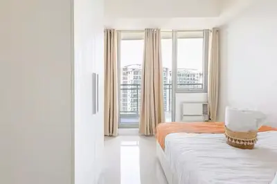 a white room with two beds and a window at Jing'sCrib 2BR Apartment by Azure Near Manila International Airport in Manila