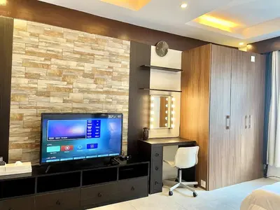 a bedroom with a television and a desk with a chair at Cozy studio suite near Eastwood QC in Manila