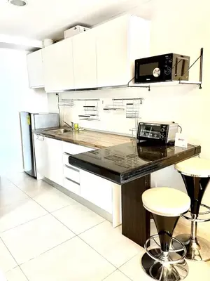 a kitchen with white cabinets and a black counter top at Cozy studio suite near Eastwood QC in Manila