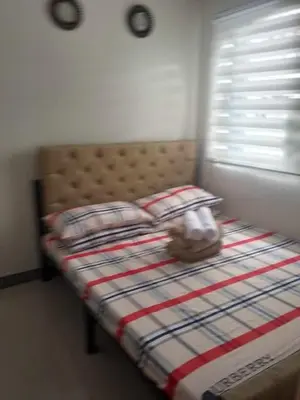 a bed with a plaid blanket and a stuffed animal on it at Charm Residences Staycation by Ashti in Manila