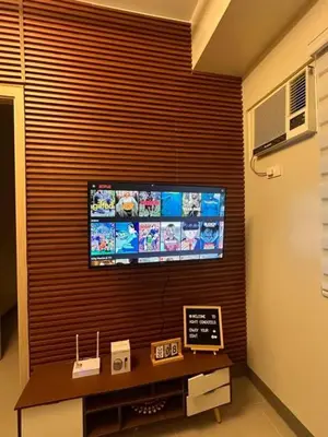 a living room with a flat screen tv on a wall at Charm Residences Staycation by Ashti in Manila