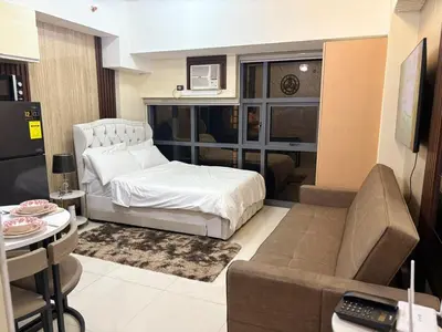 a bedroom with a bed and a couch and a table at Cozy Studio near BGC Super Fast Wi-Fi in Manila