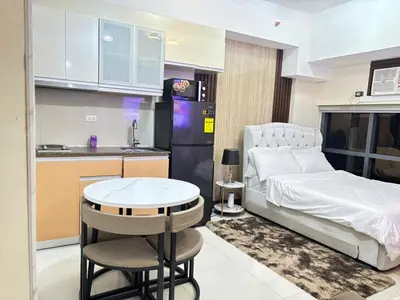 a bedroom with a bed and a table and a kitchen at Cozy Studio near BGC Super Fast Wi-Fi in Manila