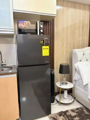a refrigerator in a kitchen next to a bed at Cozy Studio near BGC Super Fast Wi-Fi in Manila