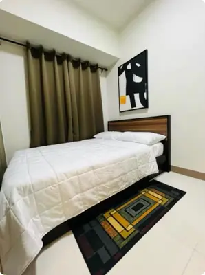 a bedroom with a bed and a rug on the floor at Coast Residences in Manila