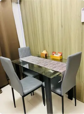 a dining room table with two chairs and a glass top at Coast Residences in Manila