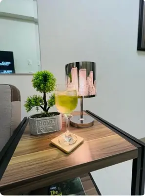 a glass of wine on a table with a lamp at Coast Residences in Manila