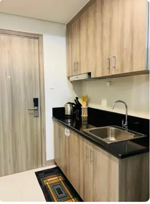 a kitchen with wooden cabinets and a sink and a door at Coast Residences in Manila
