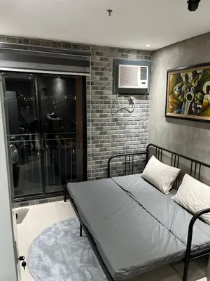 a bedroom with a bed and a brick wall at Compact Urban Studio-Type Unit in Manila