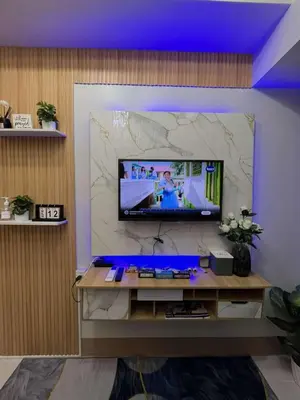 a living room with a tv on a wall at Shore 3 Residences Staycation in Manila