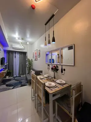 a dining room and living room with a table and chairs at Shore 3 Residences Staycation in Manila