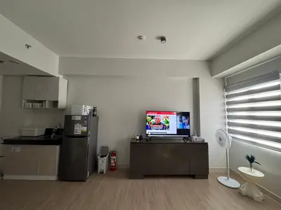 a living room with a kitchen with a tv and a refrigerator at SMDC Park Residences Unit 202 in Ibaba