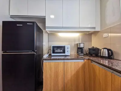 a kitchen with a black refrigerator and a microwave at Modern Condo in Prime Location in Manila