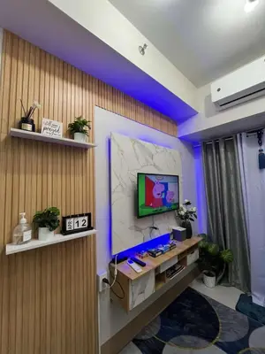 a room with a tv on a wall with purple lights at Shore 3 Residences Staycation in Manila