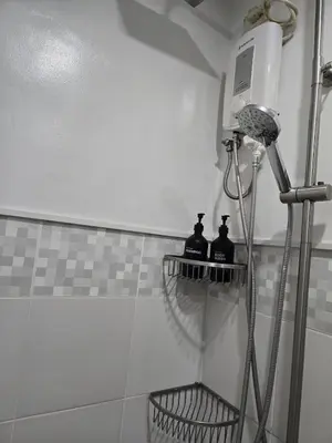 a shower in a bathroom with two bottles on shelves at BGC Center Decent 74sqm, 2br, 2baths, 4beds with maid quarter in Manila