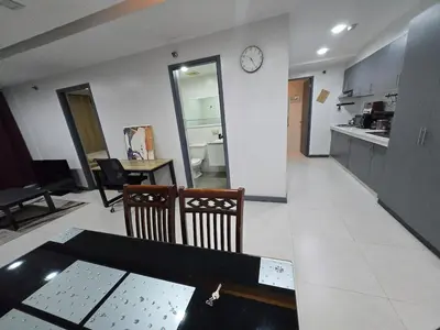 a living room with a table and a clock on a wall at BGC Center Decent 74sqm, 2br, 2baths, 4beds with maid quarter in Manila