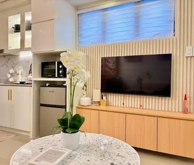 a living room with a television and a table with a flower at Elegant Staycation Near Mall of Asia with Pool Access in Manila
