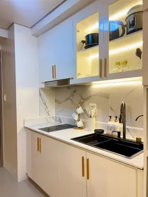 a kitchen with white cabinets and a sink at Elegant Staycation Near Mall of Asia with Pool Access in Manila