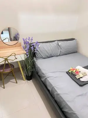 a bed in a room with a table and flowers at UNISTAY Shore 3 Tower 2 Pool Vw w Bal in Manila