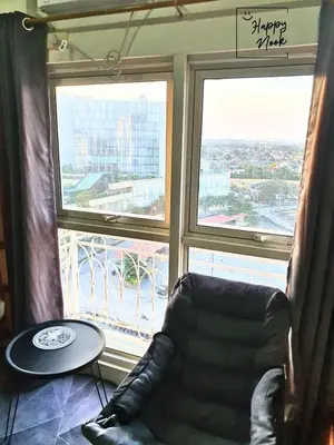 a leather chair sitting in front of a large window at Happy Nook at Holland Park Condominium in Biñan