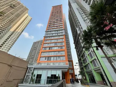 an orange building in the middle of two tall buildings at Condo in Mandaluyong with BGC Skyline in Manila