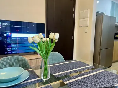 a vase of white flowers on a table with a television at Okada Manila Gentry Manor Balcony 1br Unobstructed Scenic View in Manila