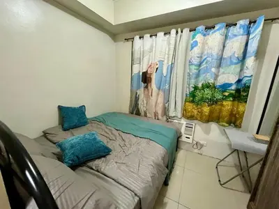 a small bedroom with a bed and a window at Sea Residences Pasay Cozy Studio Steps from SM Mall of Asia and MOA Arena in Manila