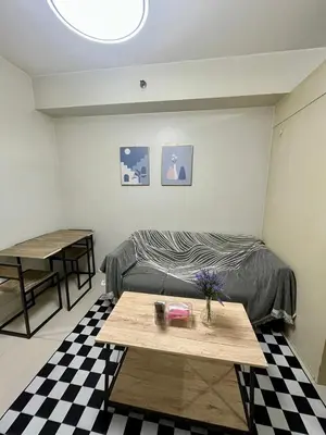 a living room with a bed and a table at Sea Residences Pasay Cozy Studio Steps from SM Mall of Asia and MOA Arena in Manila