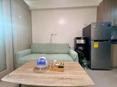 a living room with a couch and a table and a refrigerator at Shore Residences Pasay Balcony Studio Unobstructed View Near SM Mall of Asia in Manila