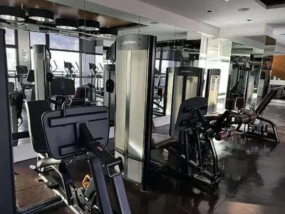 a gym with several tread machines and a mirror at Gramercy Makati Condotel in Manila